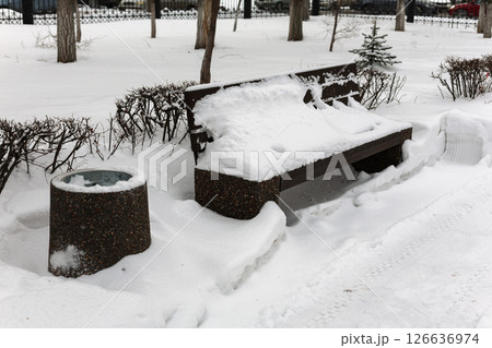 A street bench covered in snow after a snowstorm 126636974