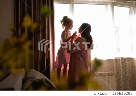 Close-up of mother and daughter exchanging loving whispers and giggles. Perfect illustration of secure attachment and childhood happiness. Close-up of mother and daughter exchanging loving whispers and giggles. Perfect illustration of secure attachment and childhood happiness. 126639295
