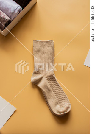Elegant neutral-toned socks against a bright yellow backdrop. Ideal for lifestyle, clothing brands, or cozy autumn concepts. Vertical flat lay. Elegant neutral-toned socks against a bright yellow backdrop. Ideal for lifestyle, clothing brands, or cozy autumn concepts. Vertical flat lay. 126639306