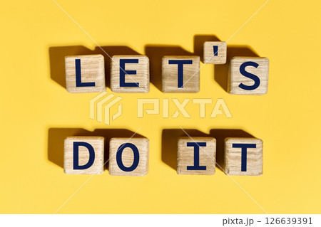 Let's do it motivation phrase on wooden blocks over yellow background Let's do it motivation phrase on wooden blocks over yellow background 126639391