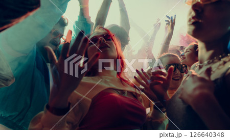 A lively party scene with people dancing energetically in vibrant lighting. A lively party scene with people dancing energetically in vibrant lighting. 126640348