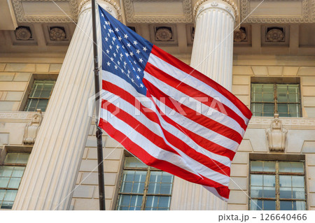 Patriotic American flag flutters in breeze near architectural columns of historic government structure at Washington DC Patriotic American flag flutters in breeze near architectural columns of historic government structure at Washington DC 126640466