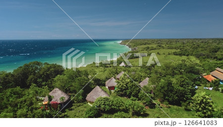 Aerial view capturing a picturesque tropical resort on Sumba Island, Indonesia, featuring traditional bungalows surrounded by lush greenery and a stunning turquoise ocean 126641083