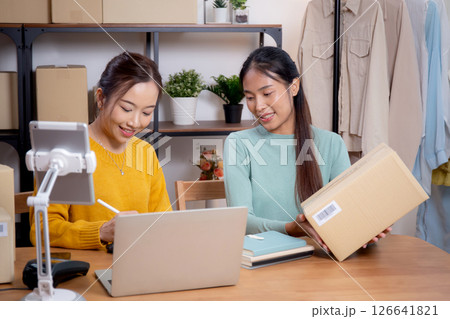 Two young asian woman working while planning online business and checking order with writing. 126641821
