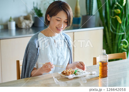 テイクアウトしたお弁当を食べる女性 126642058