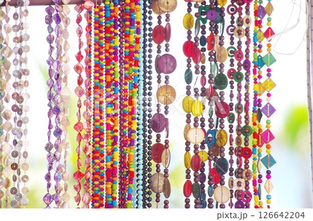 Row of colorful beads and beads are hanging from a rack Row of colorful beads and beads are hanging from a rack 126642204