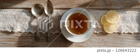 Earl grey tea is served with bergamot slices and vintage teaspoons under warm natural light Earl grey tea is served with bergamot slices and vintage teaspoons under warm natural light 126643222