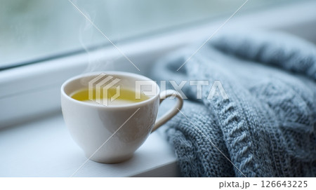 Enjoying a warm cup of citrus earl grey tea on a moody afternoon, wrapped in comfort Enjoying a warm cup of citrus earl grey tea on a moody afternoon, wrapped in comfort 126643225