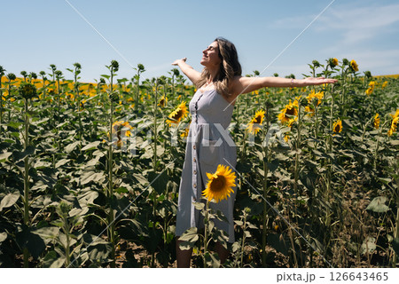 Happy woman arms raised and enjoying in sunflower field. 126643465