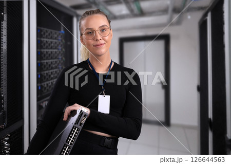 Smiling professional technician holding network equipment in a modern server room setup Smiling professional technician holding network equipment in a modern server room setup 126644563