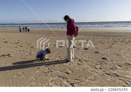 Mother and son playing on sandy beach by the ocean 126645245