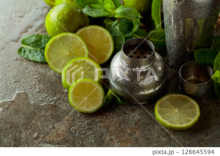Shaker, limes, and  fresh mint branches on a stone table. 126645594