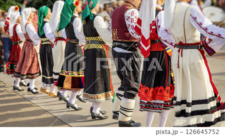 Colorful line of dancers in traditional costumes . Men and women dancing on folk festival outdoor. Bulgarian culture concept, cultural expression, unity , traditional dance celebration 126645752