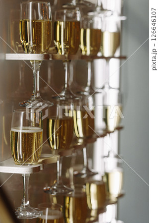 Glasses of champagne on modern wall-mounted shelf with reflections and soft light indoors 126646107