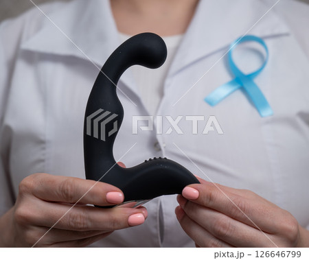 Female doctor holding prostate massager and blue ribbon. Symbol of fight against prostate cancer.  Female doctor holding prostate massager and blue ribbon. Symbol of fight against prostate cancer.  126646799
