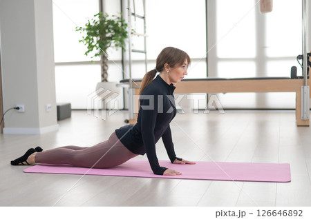 Concentrated woman doing pilates in studio alone. Concentrated woman doing pilates in studio alone. 126646892