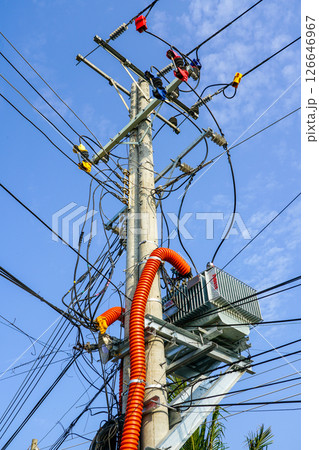 Tangled overhead electrical wires on a power pole under blue sky in a tropical Southeast Asian town Tangled overhead electrical wires on a power pole under blue sky in a tropical Southeast Asian town 126646967