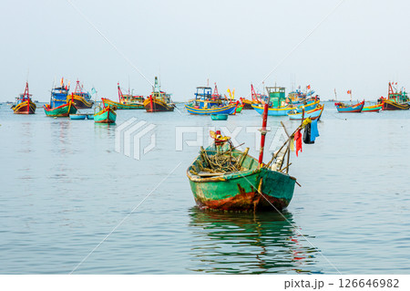 Colorful wooden fishing boats floating in the calm waters of Vietnamese harbor, early morning light Colorful wooden fishing boats floating in the calm waters of Vietnamese harbor, early morning light 126646982