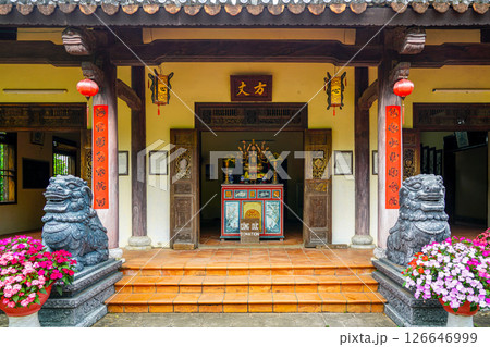 Entrance of a traditional Vietnamese temple with guardian lion statues, lanterns, and donation altar 126646999