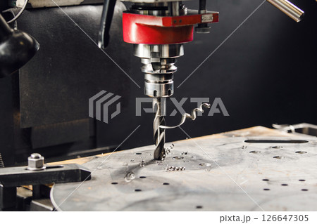 Drilling the under bolt hole. Vertical drill makes holes in metal part.  126647305
