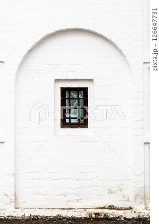 barred window in old white monastery wall 126647731