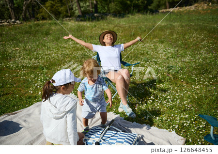 Family Enjoying a Picnic Outdoors on a Sunny Day in a Blooming Meadow Family Enjoying a Picnic Outdoors on a Sunny Day in a Blooming Meadow 126648455