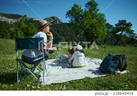 Family Enjoying a Relaxing Picnic in a Scenic Mountain Park Landscape Family Enjoying a Relaxing Picnic in a Scenic Mountain Park Landscape 126648458