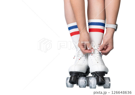 Young female tying laces on white roller skates with red and blue striped socks Young female tying laces on white roller skates with red and blue striped socks 126648636