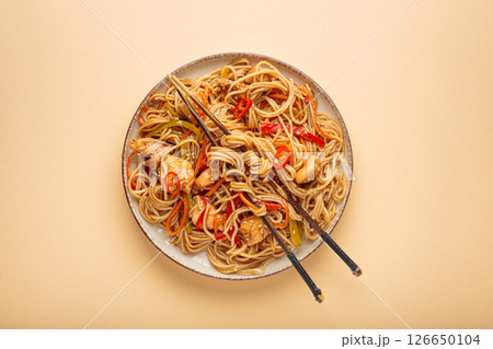 Asian chicken noodles with vegetables and chopsticks on beige background top view 126650104