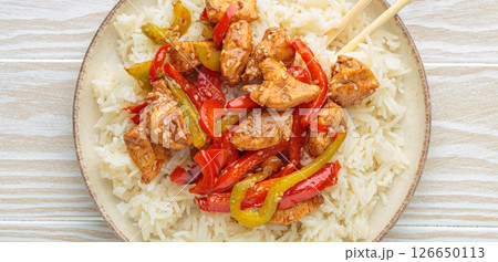 Chicken stir fry with peppers and rice on a plate with chopsticks top view Chicken stir fry with peppers and rice on a plate with chopsticks top view 126650113