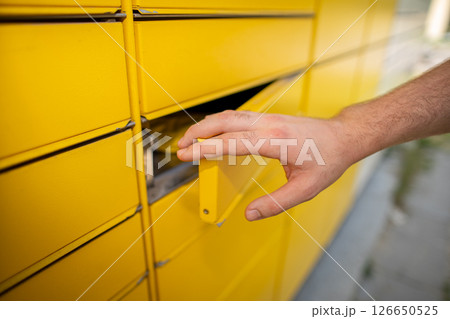 Hand Opening the Bright Yellow Mailbox Slot for Receiving Packages and Mail Items Hand Opening the Bright Yellow Mailbox Slot for Receiving Packages and Mail Items 126650525