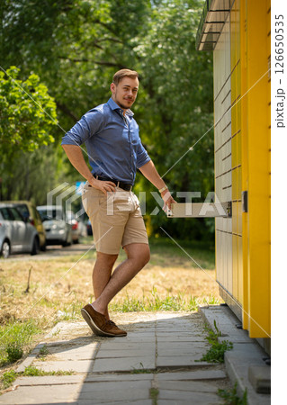 A young man is joyfully approaching a vibrant and colorful building during a sunny summer day 126650535