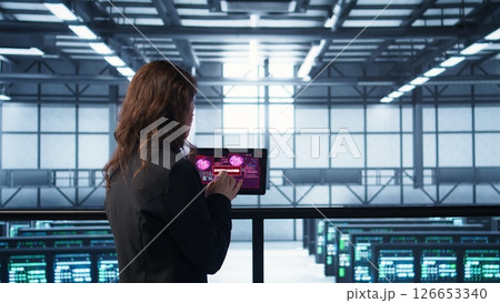 Data center engineers struggling to contain virus infestation, working on securing servers. Team of server farm employees detecting hacker attacks on tablet, fighting back, camera B 126653340
