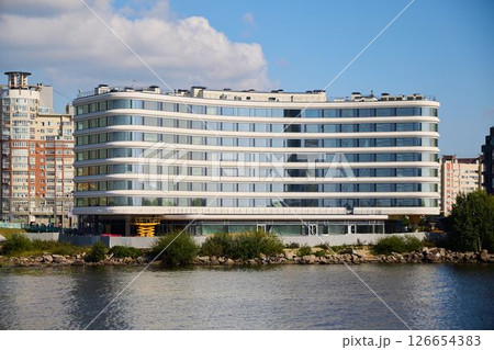 A Modern Curved Building Gracefully Situated Near a Waterway Beneath a Clear Blue Sky 126654383