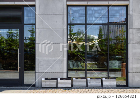 A modern building facade with reflective windows and display boards, an impressive landmark A modern building facade with reflective windows and display boards, an impressive landmark 126654821