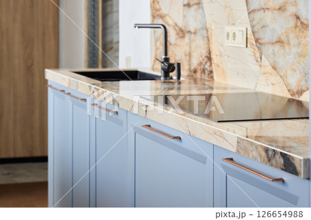 A Modern Kitchen Featuring a Sleek and Stylish Marble Countertop Accompanied by Blue Cabinets 126654988