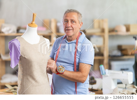 Man tailor adjusts clothes on mannequin Man tailor adjusts clothes on mannequin 126655555
