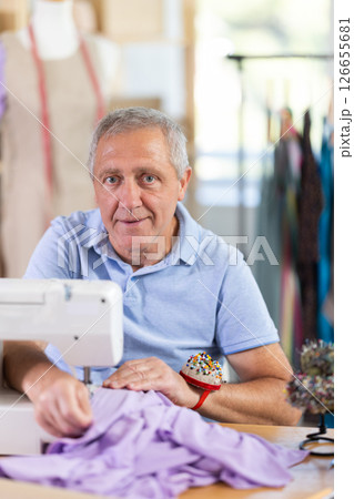 Man tailor sews on sewing machine in workshop 126655681