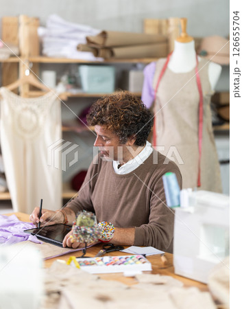 Man tailor creates sketch of dress on tablet 126655704