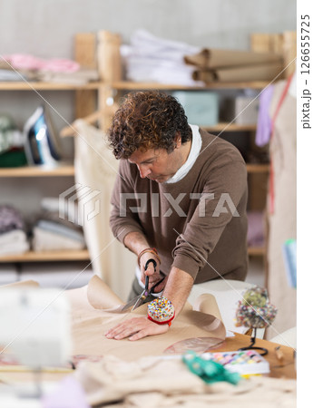 Man tailor cuts paper dress pattern and work with hand snip Man tailor cuts paper dress pattern and work with hand snip 126655725