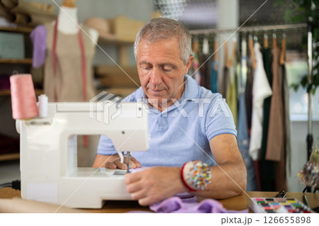 Man tailor sews on sewing machine in workshop 126655898