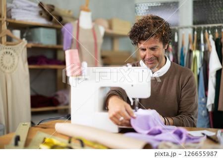 Man working on a sewing machine in a workshop 126655987