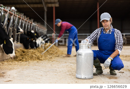 Adult male farmer with can works on dairy farm Adult male farmer with can works on dairy farm 126656029