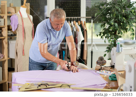 Mature man cutting fabric Mature man cutting fabric 126656033