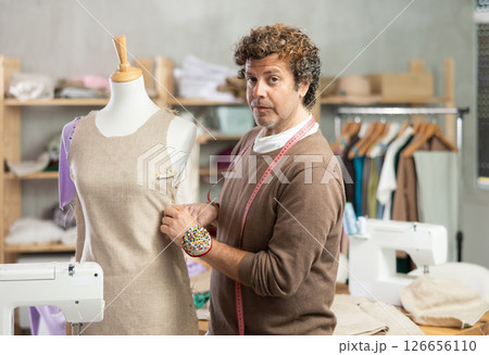 Man tailor adjusts clothes on mannequin Man tailor adjusts clothes on mannequin 126656110