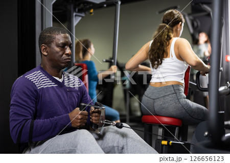 African man doing exercises on cable row machine in gym 126656123