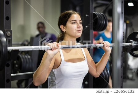 Sportswoman doing exercises with a barbell in gym 126656132