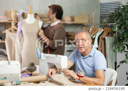 Mature man tailor at work, other man work with mannequin in background 126656190