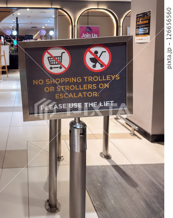 Sign indicating no shopping trolleys or strollers allowed on escalators in a shopping center Sign indicating no shopping trolleys or strollers allowed on escalators in a shopping center 126656560