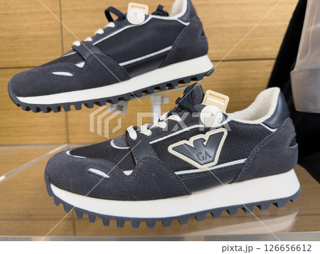 Stylish black and white Emporia Armani sneakers displayed on a glass shelf in a modern retail store 126656612